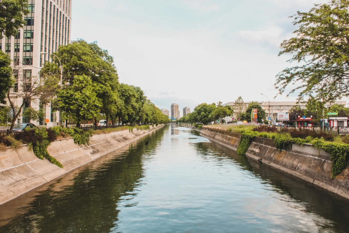 Canal de drenagem urbana com margens revestidas e árvores