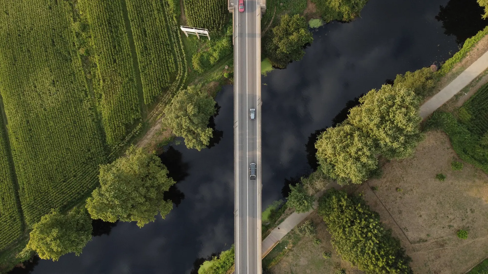 Rio atravessado por estrada, visto de cima, com vegetação nas margens